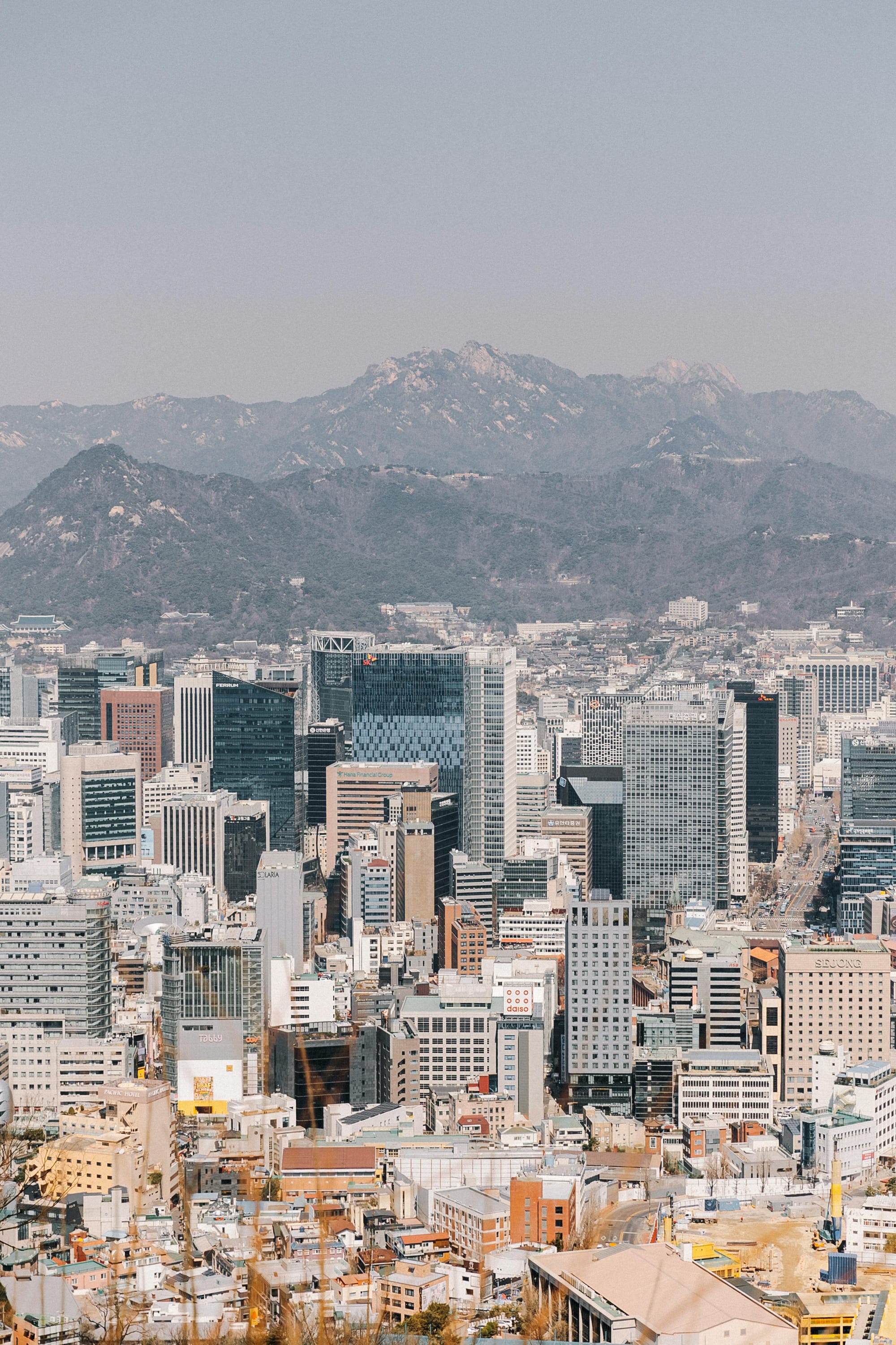 <img src="https://www.pexels.com/ko-kr/photo/20837362/.jpg" alt="Seoul skyline with dense office towers and Bukhansan mountain ridge in the background." />